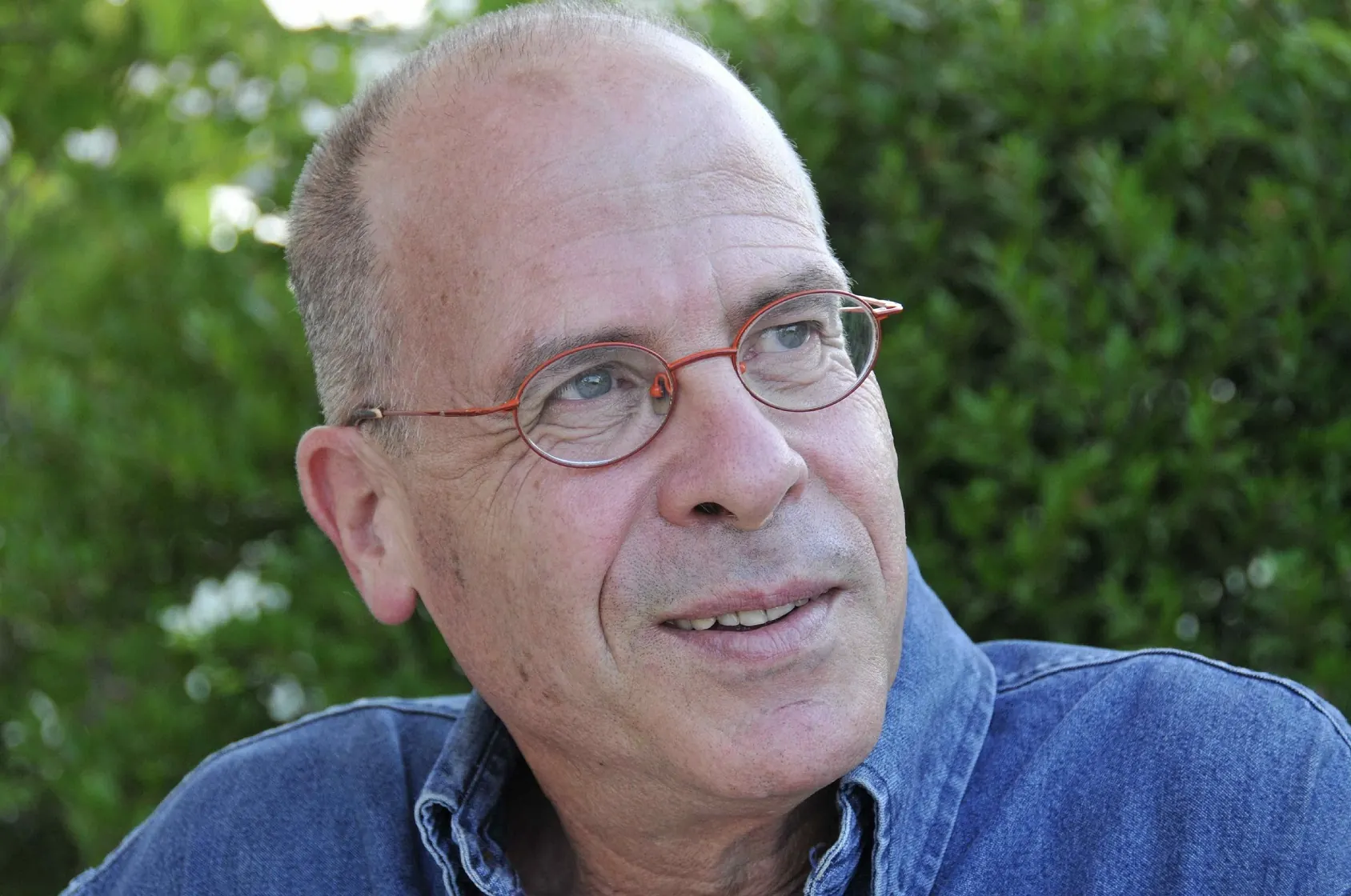 מאיר שלו מצולם בחוץ על רקע עצים