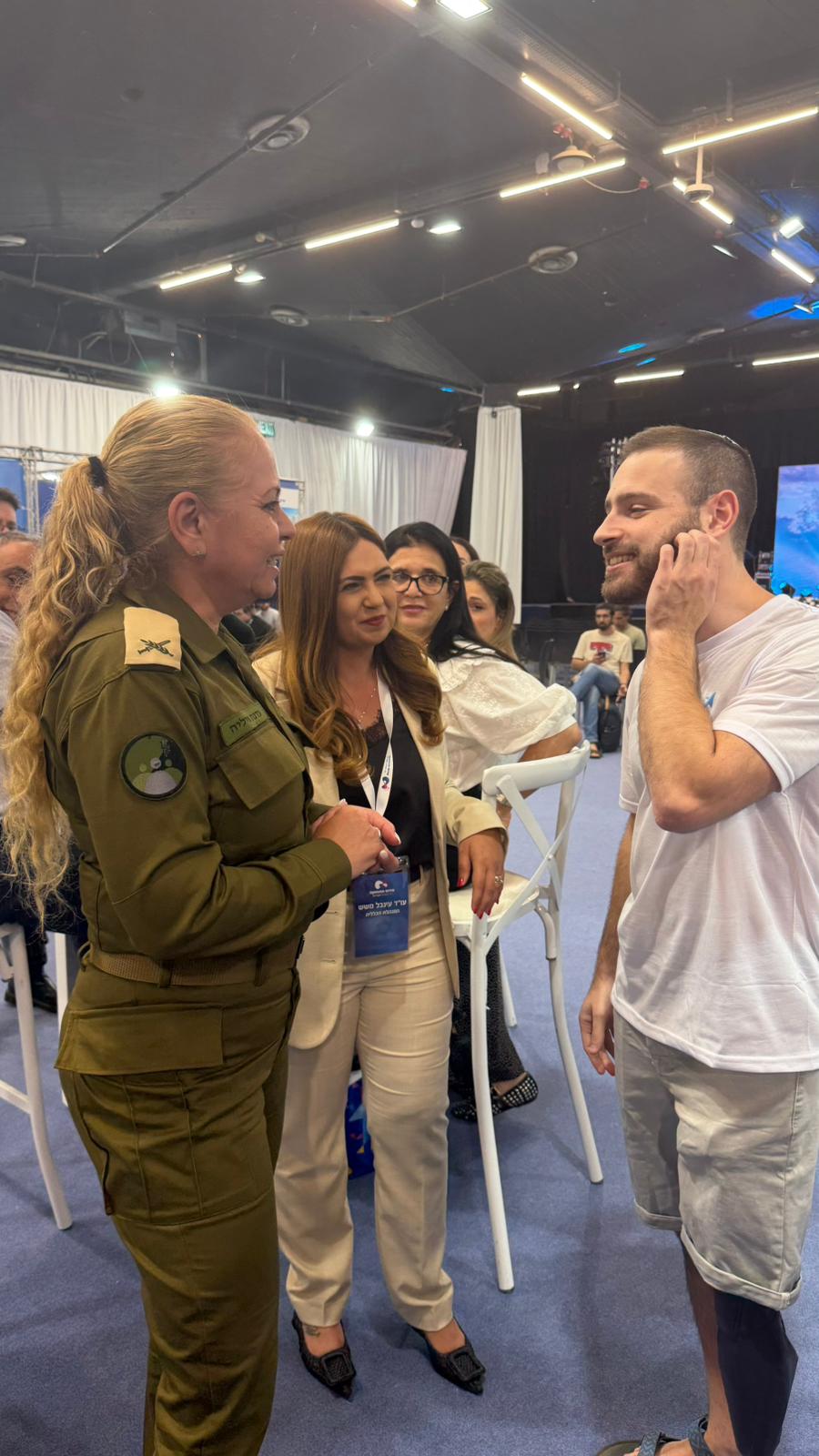 קצינה, נציגת שירות התעסוקה ומשתתף משוחחים ביריד תעסוקה
