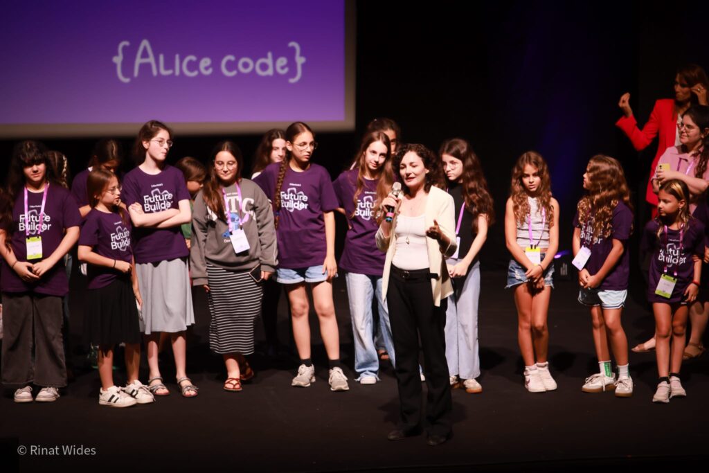 נסטיה אוצ'קובסקי עומדת על במה לצד ילדות ונערות בכנס AliceCode Summit 2026