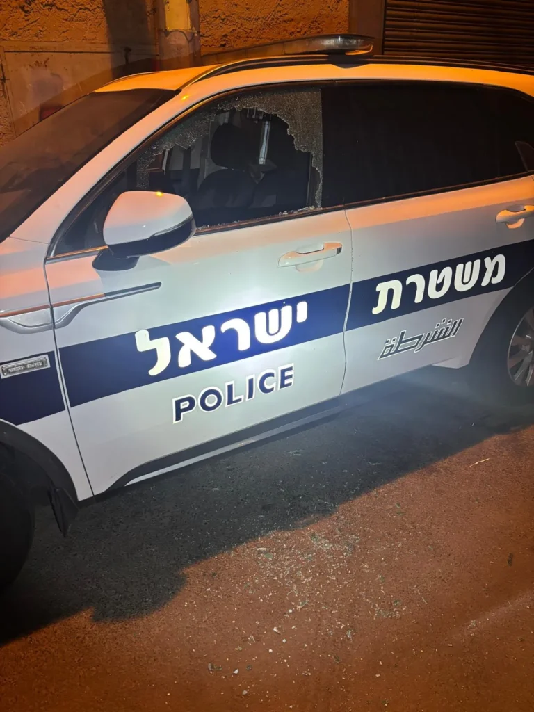 ניידת משטרה חונה בלילה ובה חלון אחורי מנופץ